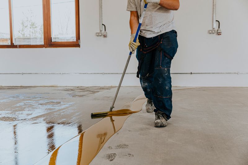 Epoxy floor installer applying a coating in a Brighton garage