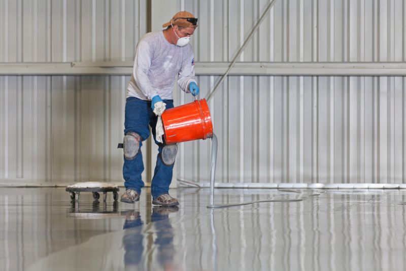 worker pouring self levelling epoxy mixture